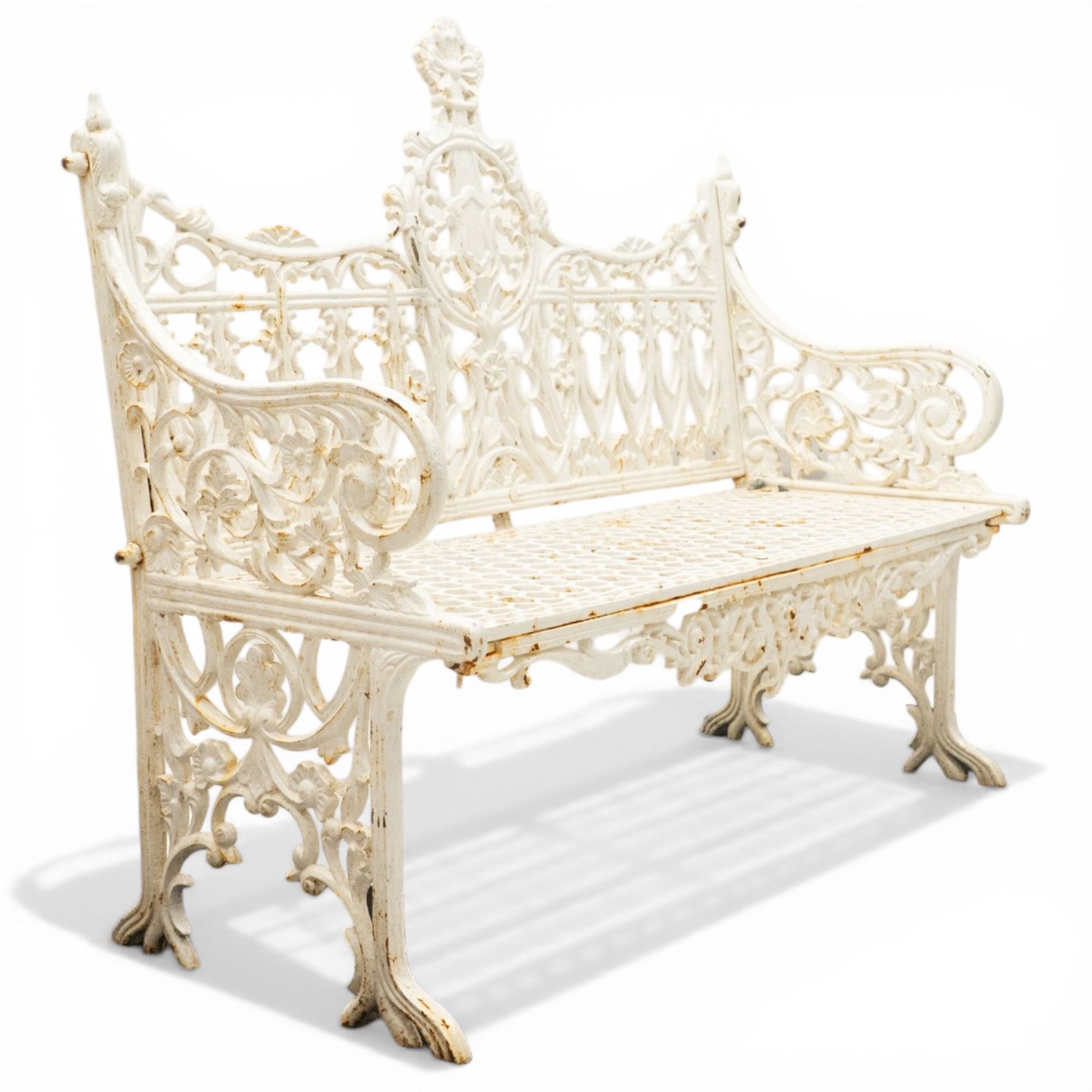 Victorian revival heavy cast iron garden bench, ornate back rest with scrolls, floral motifs and central crest, pierced lattice seat, curved arms and decorative legs, painted in antique white, in the Gothic Coalbrookdale style