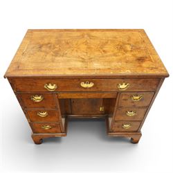 George II figured walnut kneehole desk, the rectangular book-matched veneer top with feather and cross-banding, fitted with single frieze drawer over a short drawer and central recessed cupboard, flanked by three drawers to each side, lower moulded edge on bracket feet