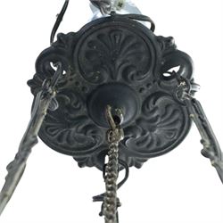 Late 19th century wrought metal hanging ceiling lamp, the ornate pierced central reservoir-form body with mounted eagle, three scrolling branches fitted with three clear glass chimney shades, suspended by decorative chains from a pierced ceiling rose