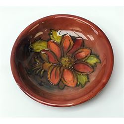A Moorcroft flambe dish, circa 1950, decorated in the Clemmatis pattern, marks beneath obscured by glued on fabric hanger, D19cm. 