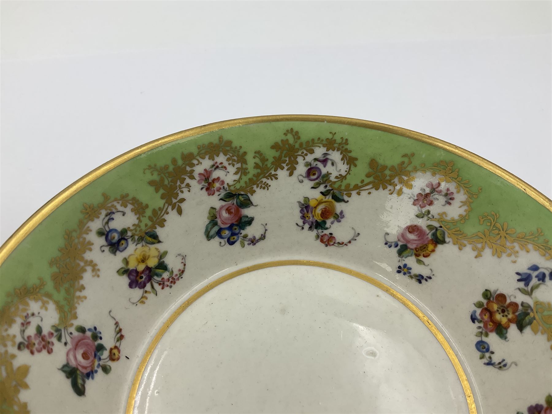 Sèvres soft paste porcelain coffee can and saucer with date code for 1754, painted and gilded with flowers, dangling from the shaped green border, interlaced LL monogram enclosing the date letter A above painters mark for Dodin, coffee can H7cm, saucer D14.5cm