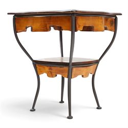 Art Nouveau style occasional table, serpentine shaped top with dark moulded edge, shaped apron and lower shelf, raised on four curved metal supports