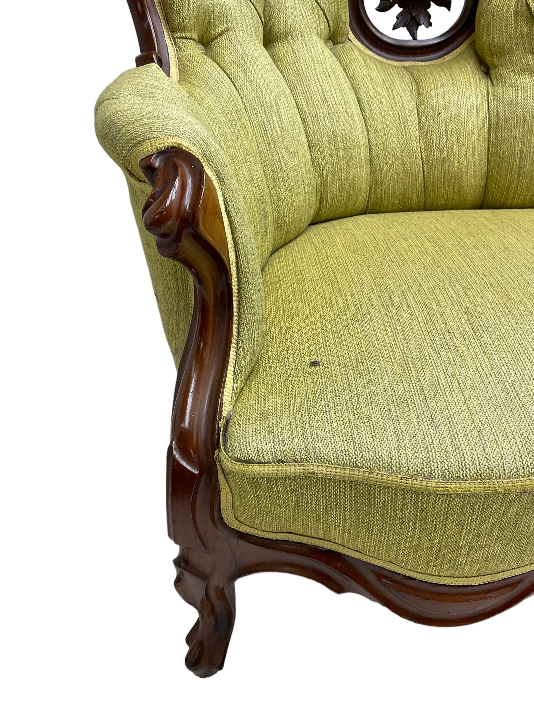 Victorian walnut settee, triple back with pierced and scroll-carved cresting rails over carved fruit and foliage decoration, upholstered in buttoned green fabric, serpentine seat and carved apron, on cabriole feet