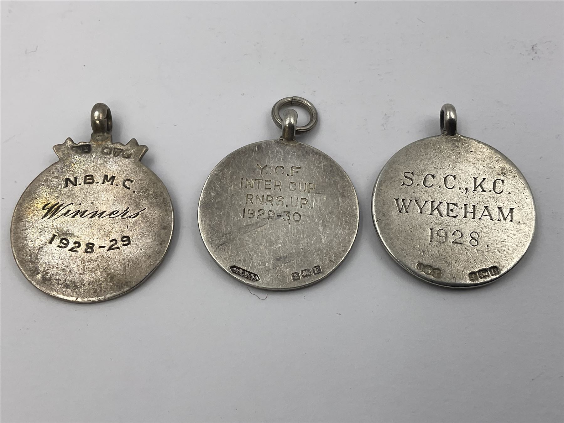 Seven early 20th century silver gold faced cartouche fobs, to include a circular example, with rose gold border and cartouche within an embossed yellow gold border, engraved verso, and a double sided example, all hallmarked with various dates and makers
