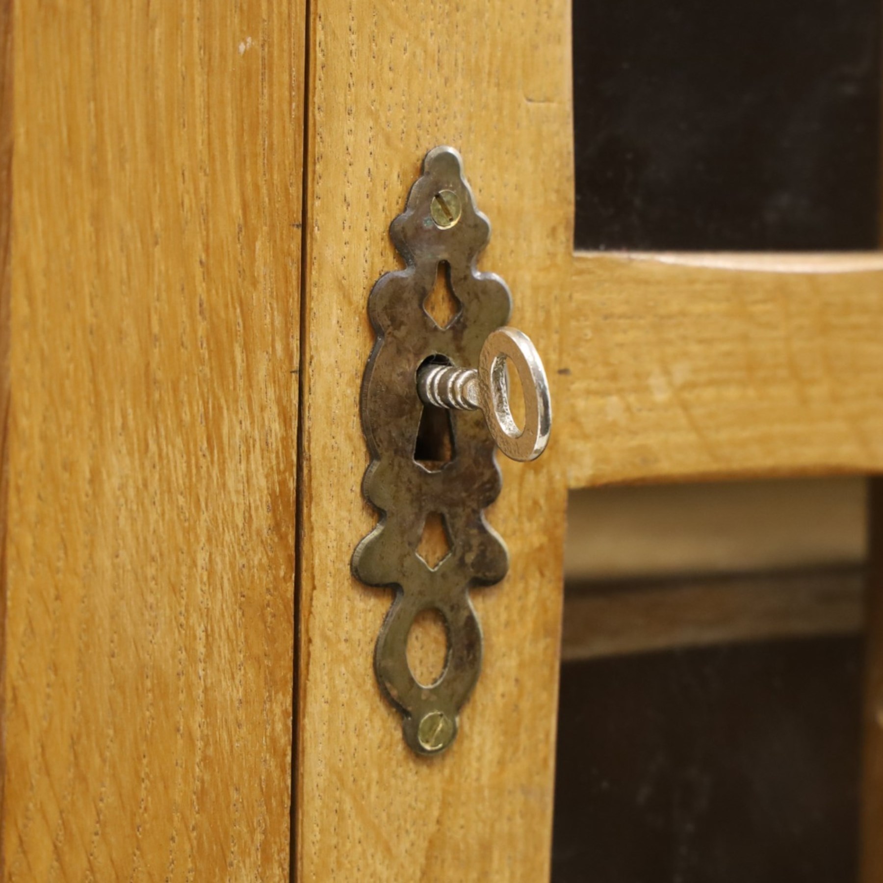 Acorn Industries - oak floor-standing corner cabinet, the top fitted with astragal glazed door enclosing four shaped shelves, the base with single panelled cupboard over two drawers, raised on four stepped feet, carved with acorn signature to top and base, by Alan Grainger, Brandsby