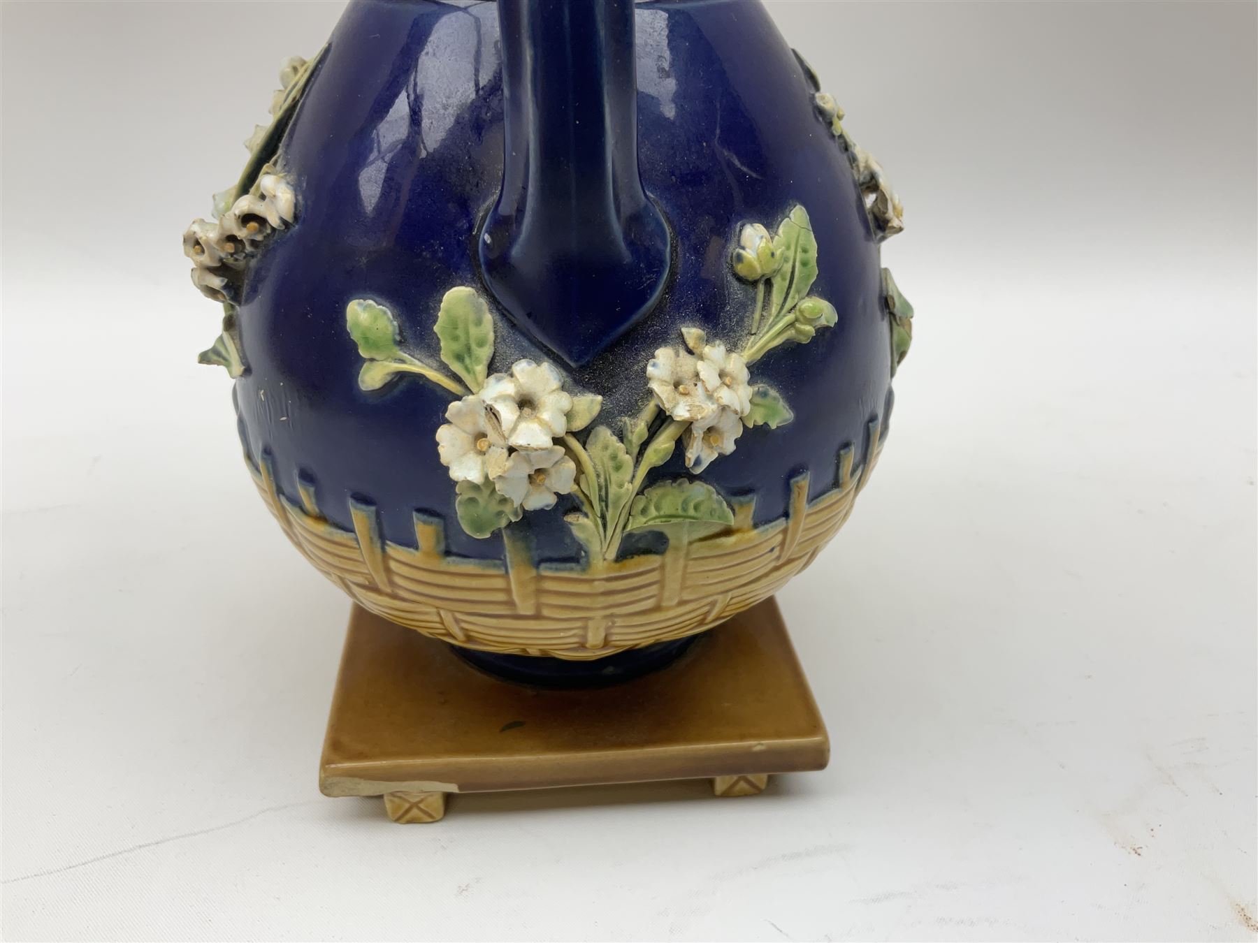 Minton majolica vase, the squat body with twin handles, with part osier moulding and applied Spring flowers against a cobalt blue ground, upon integral square base, impressed beneath Minton 1316, H16.5cm