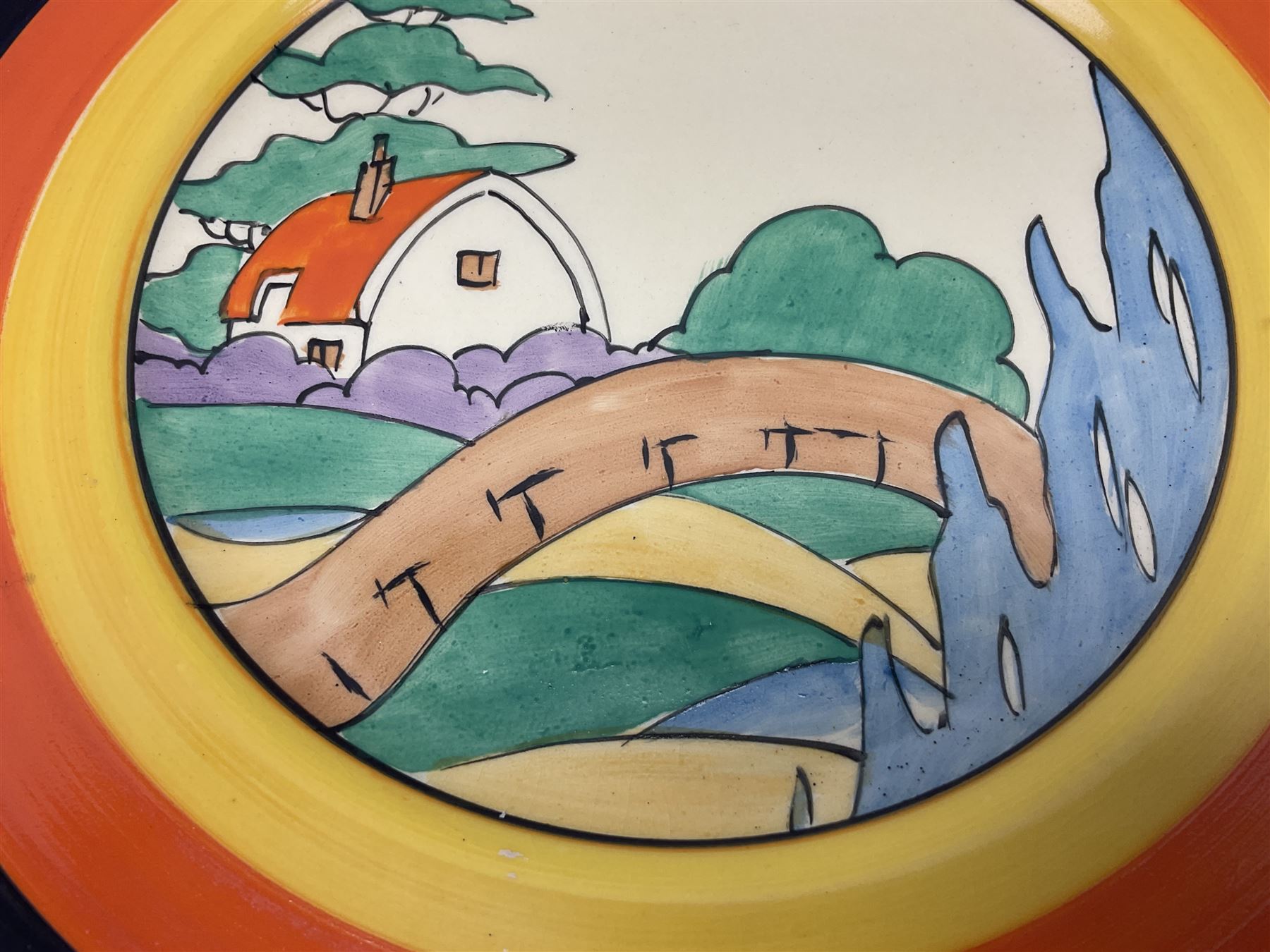 Clarice Cliff Bizarre for Newport Pottery Orange Roof Cottage pattern plate, circa 1932, hand painted with a stylised cottage and bridge landscape with yellow, orange and black banding, black printed mark beneath, D22cm 