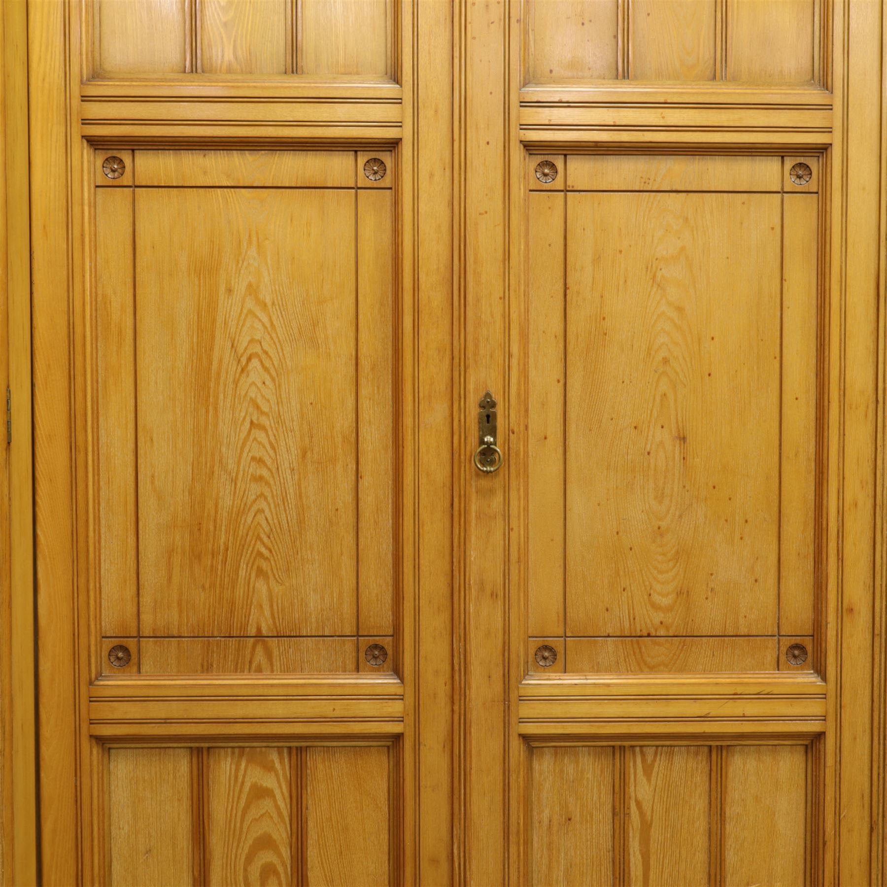 Gothic revival ash breakfront wardrobe in the manner of Charles Bevan, the four fielded panelled doors flanking a central mirrored door, opening to reveal an fitted interior with hanging rails and compartment shelves and drawers, upon a shaped plinth base with bracket cut feet

