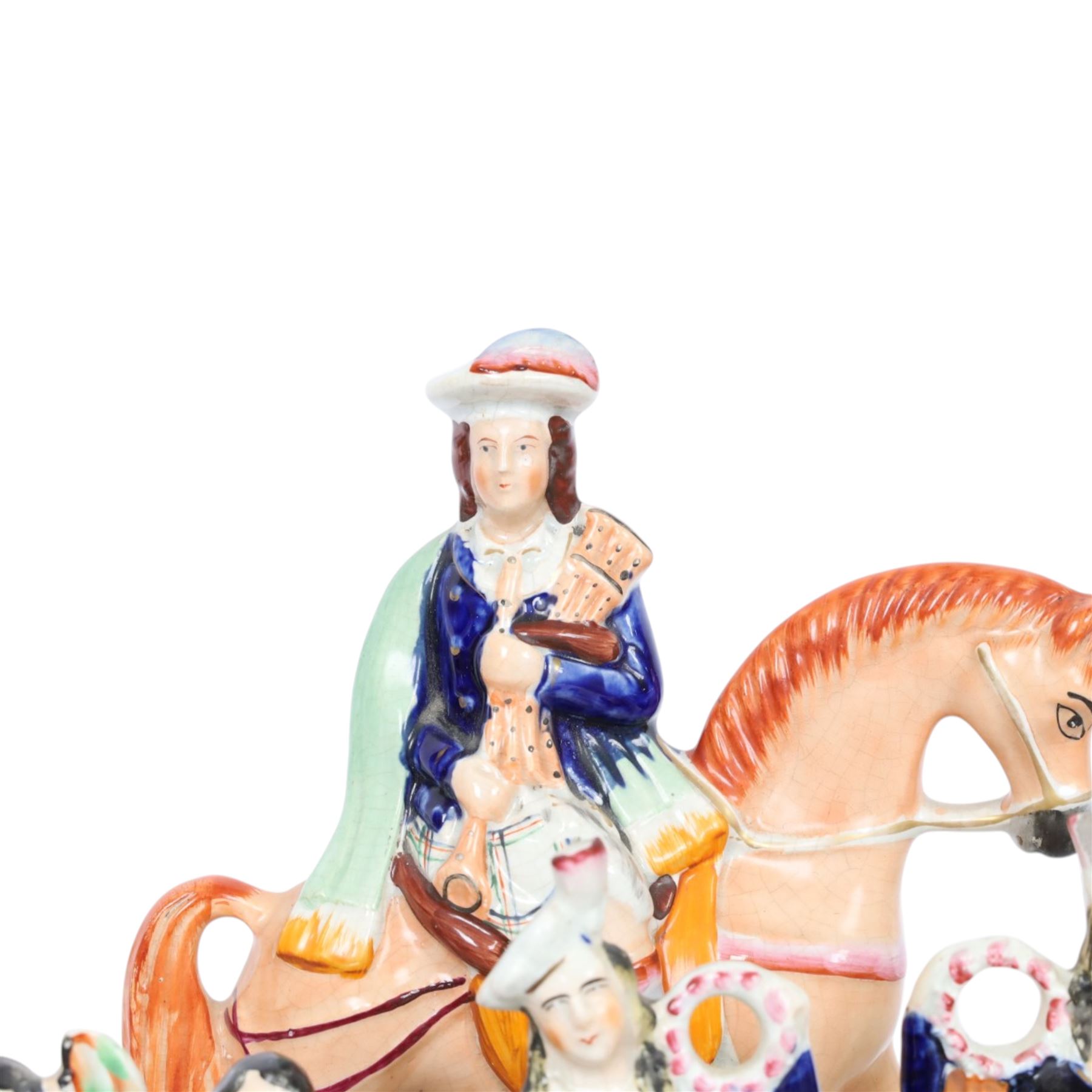 Group of Staffordshire figures, mostly Highland examples, to include figure with bagpipes upon horseback, figure group of Highland Mary and Byron, two figure groups depicting pair of dancers holding flag aloft, two pairs of recumbent sheep, one pair with fags, largest example H30cm