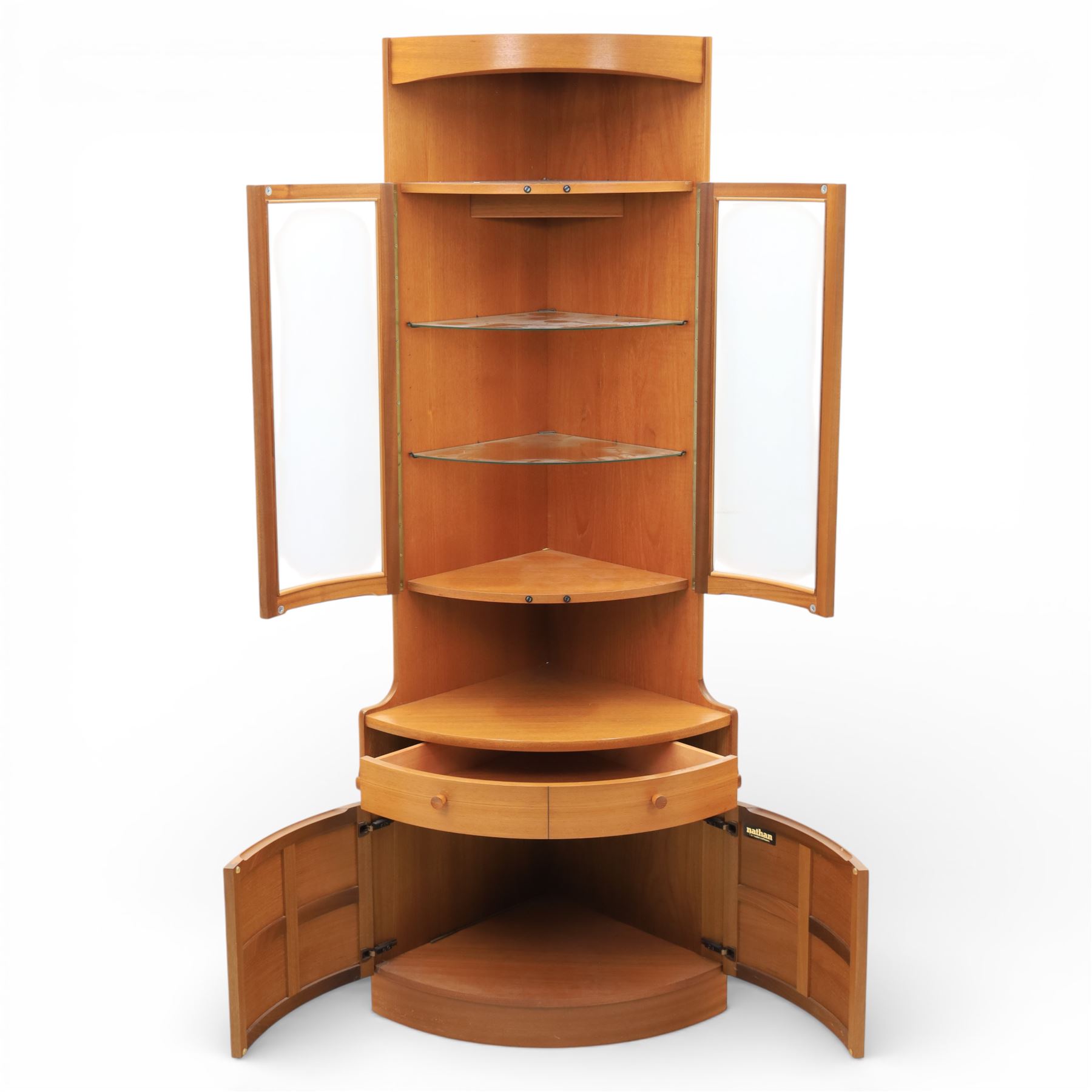 Nathan - 'Squares' corner cabinet, the upper section enclosed by two curved glazed doors with glass shelves, over a shaped base fitted with a single frieze drawer and panelled twin cupboard doors