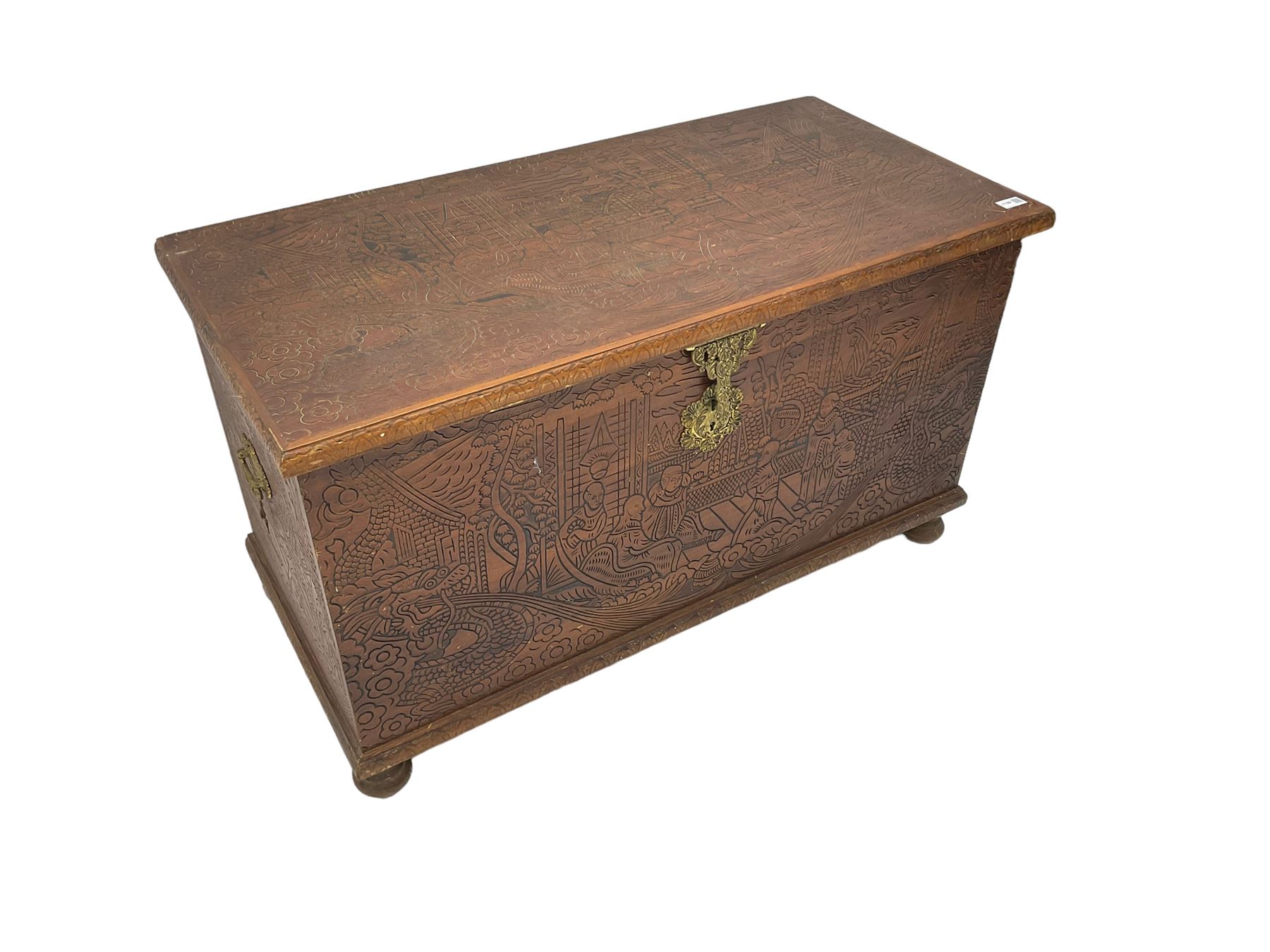 Hong Kong camphor wood chest, rectangular hinged top, carved all over with traditional scenes and dragon boats, on bun feet