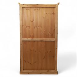 Modern stripped pine double wardrobe, with stepped cornice over upper cupboard doors and two full-height fielded panel doors, fluted stile detailing, ebonised knob handles, and plinth base