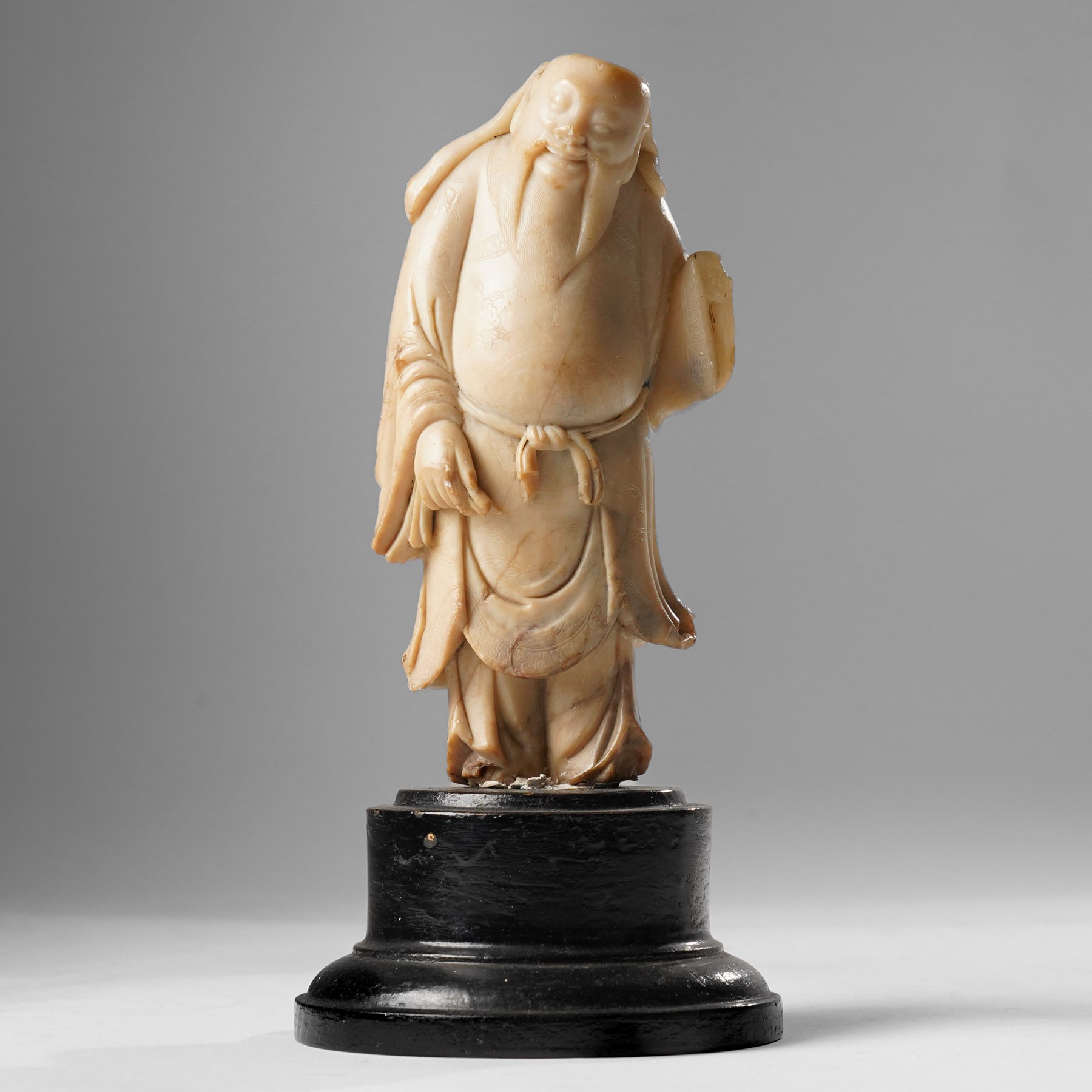 Soapstone carving of an immortal, possibly Zhongli Quan, on ebonised wooden base, including base H22cm