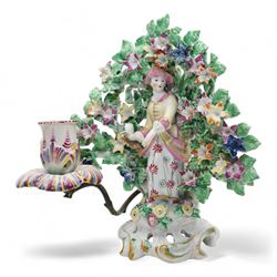 Pair of Bow porcelain 'New Dancers' candlesticks, standing before flowering bocages, and wearing brightly coloured flowered clothes, each supporting to left and right a tôle peinte branch terminating in a leaf moulded nozzle, on scrolling footed bases, red anchor and blue/red dagger marks beneath, H19cm x W18cm (2)