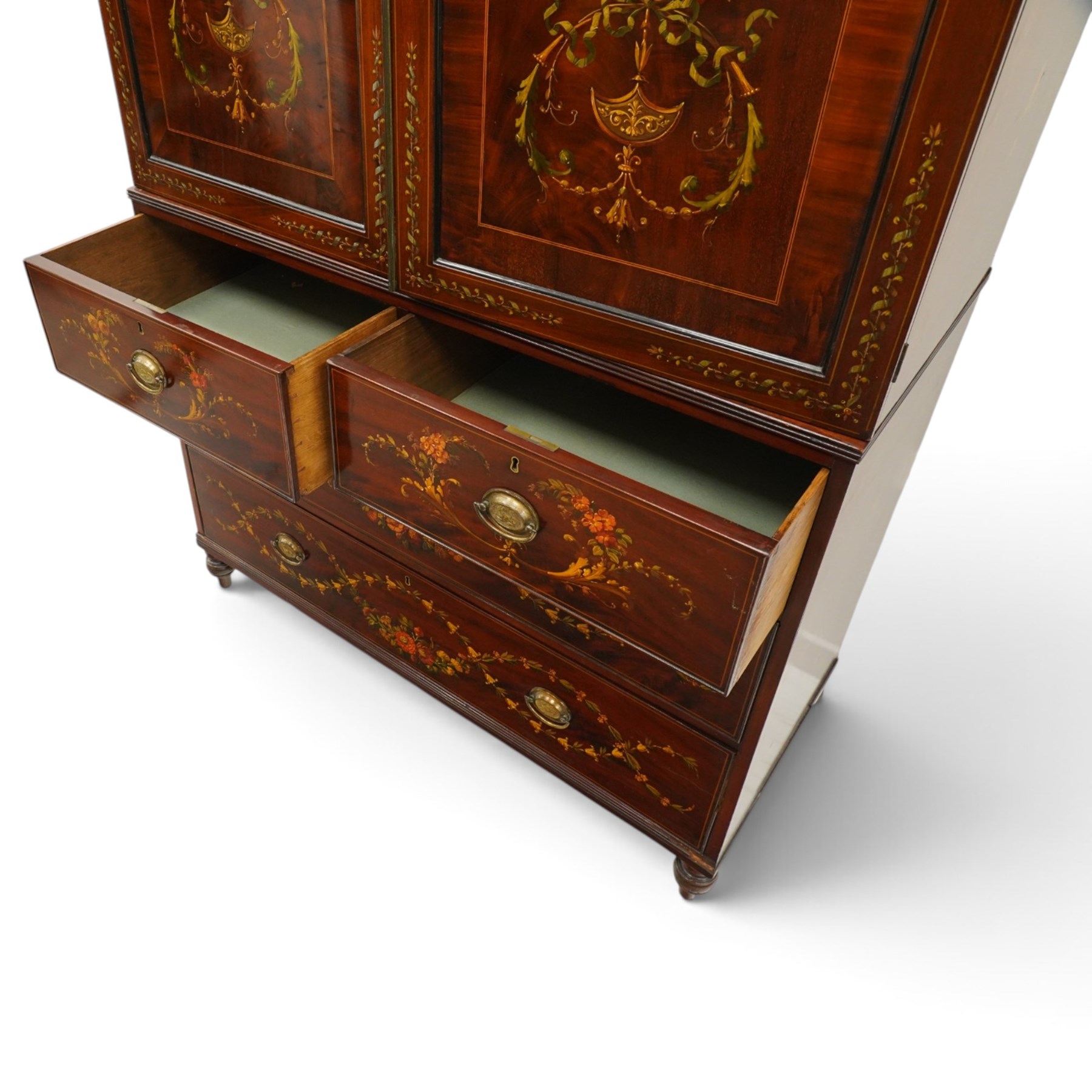 19th century French Louis XVI design mahogany and polychrome painted gentleman's press wardrobe - projecting cavetto cornice with urn and bellflower painted frieze, the twin doors with classical figural medallions surmounted by urns and festoon decoration with scrolling acanthus leaves, enclosing five sliding trays, the base fitted with two short over three long cock-beaded drawers, the facias painted with interlocking swags and garlands of bouquets with recumbent lion brass handle-plates, lower reeded edge on turned feet