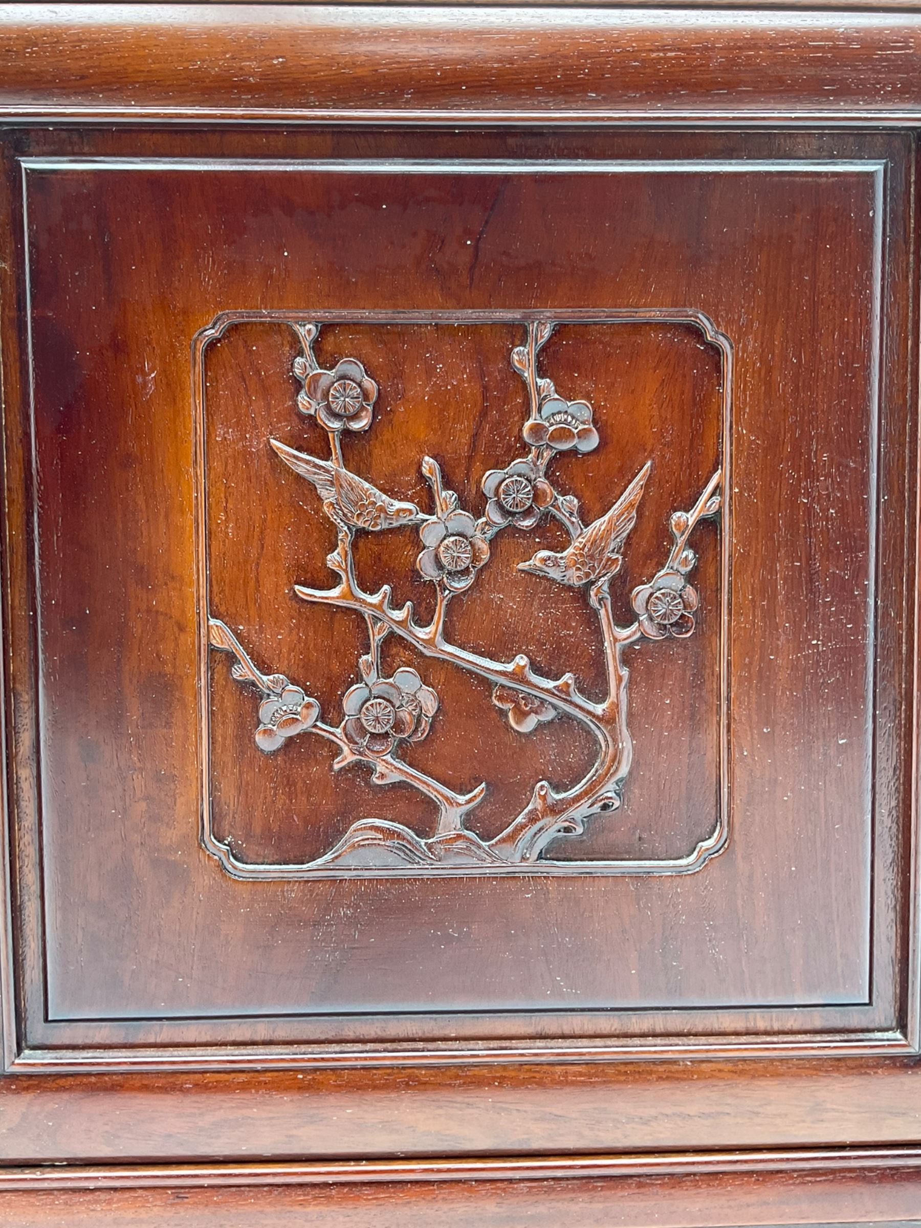 Chinese hardwood sideboard, three drawers above four cupboards, the doors relief carved with flowers and birds 