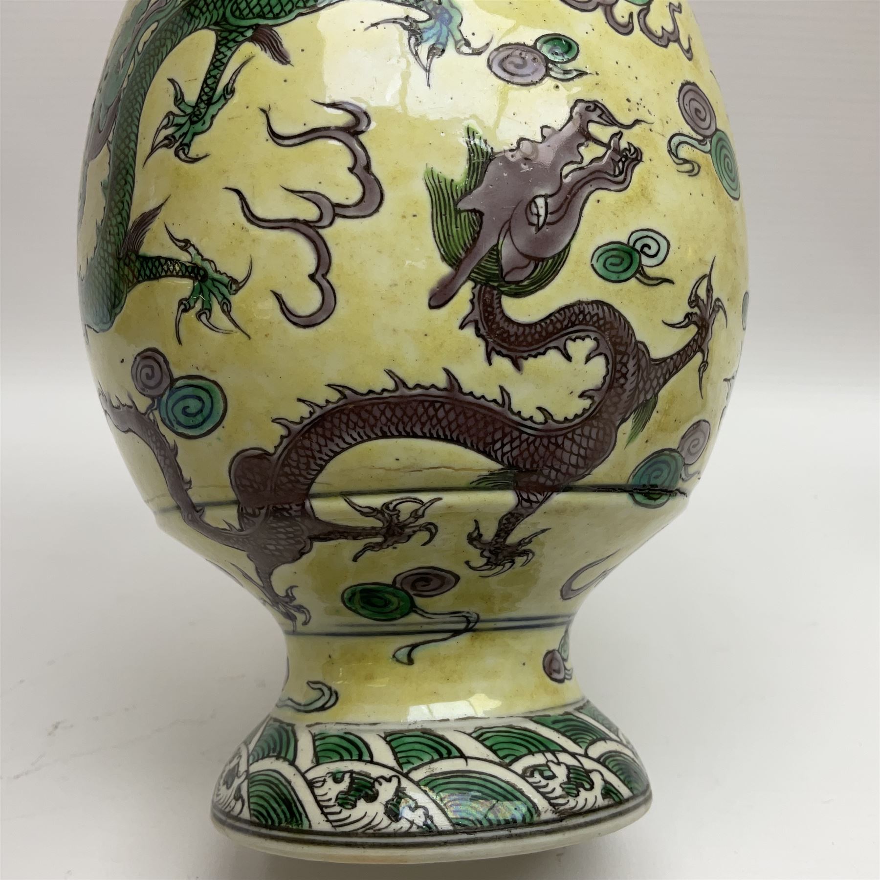 20th century Chinese Famille Verte vase, of slender ovoid form with tapering neck and flared rim, decorated with green and grey enamel with dragons chasing flaming pearls amongst auspicious clouds upon a yellow ground, H30cm