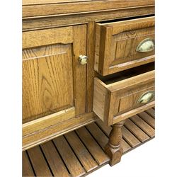 Light oak dresser, projecting cornice over display cabinets, shelves and drawers, the dresser base fitted with panelled cupboards and two drawers, on turned supports and pot board base