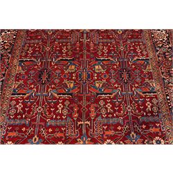 North West Persian Karadja hand-knotted carpet, deep red field decorated with an all-over lattice design of elongated geometric devices interspersed with rosettes and angular palmettes, enclosed by a dark indigo main border of stylized floral and geometric motifs between multiple guard stripes, with cotton fringe ends 