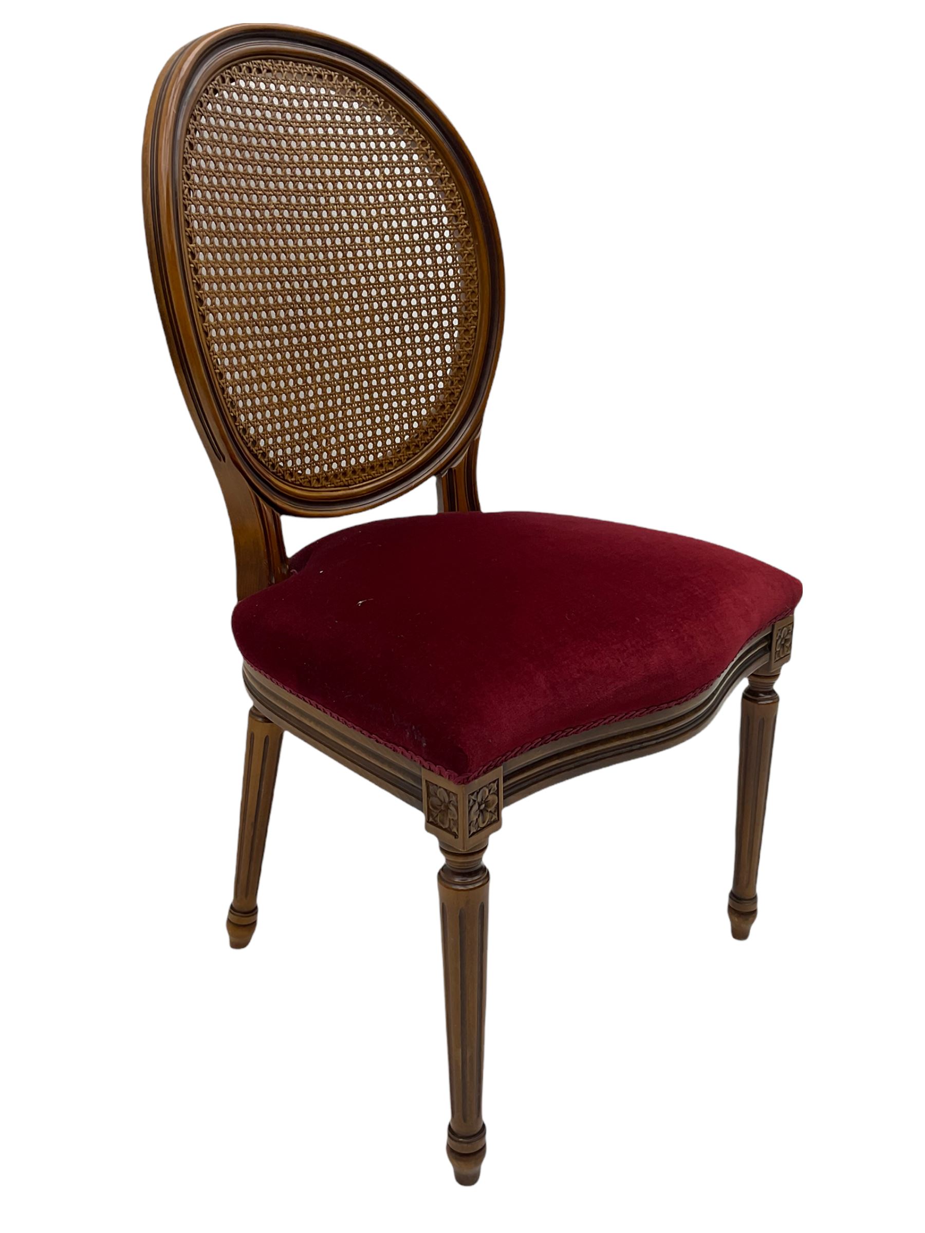 Set six French style walnut finish dining chairs, oval cane bergere backs over serpentine seats upholstered in red, flower head carved fluted supports