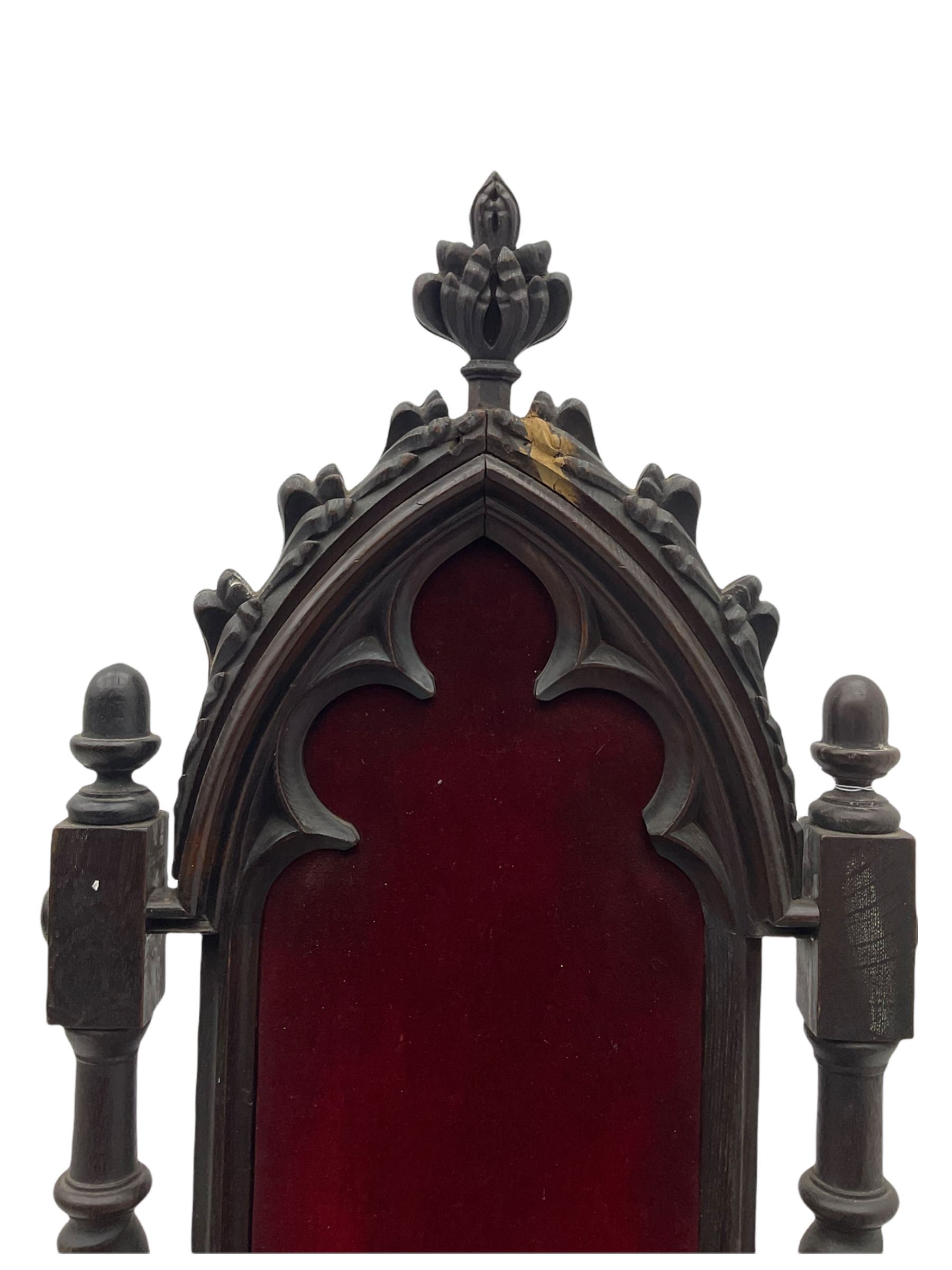 Victorian oak and wrought metal Gothic open armchair, the pointed arched back carved with foliate, cusped inner arch upholstered in red, spiral turned uprights and supports, with arms made of spiral forged metal