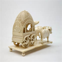 Early 20th century Indian carved ivory figure group, modelled as a foliate detailed carriage containing passenger and driver, drawn by two oxen, raised upon a rectangular base with bun feet, L11.5cm, H9.5cm