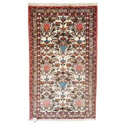 Iranian Persian style rug, repeated stylised vase and floral motifs arranged symmetrically...