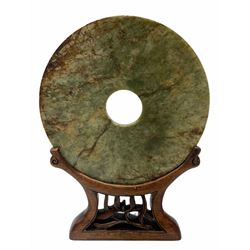 Large Chinese green and russet jade Bi-Disc, engraved with Taotie masks and tigers in the style of the Western Han dynasty, upon carved hardwood stand, disk D21cm