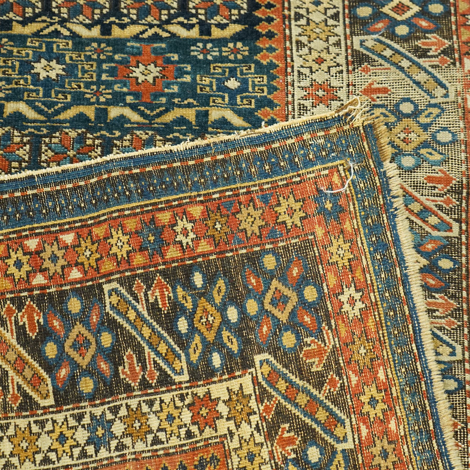 Two antique Caucasian Shirvan rugs, indigo field decorated with horizontal bands of small geometric floral and star motifs within multiple finely drawn borders featuring diamonds, rosettes, and stylized leaves in a palette of madder red, ivory, ochre, and pale blue, with fringe ends, 195x137cm, together with a similar smaller rug, 143x96cm