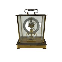 A  mid-20th century German Kieninger & Obergfell, “Kundo” battery operated 
mantle clock, rectangular case with four bevelled viewing panels and carrying handle, electrically operated solenoid pendulum powered via a battery housed in the base, skeleton movement with a visible escapement viewed through an open chapter ring with Arabic numerals and gilt baton hands.

