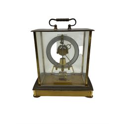 A  mid-20th century German Kieninger & Obergfell, “Kundo” battery operated 
mantle clock, rectangular case with four bevelled viewing panels and carrying handle, electrically operated solenoid pendulum powered via a battery housed in the base, skeleton movement with a visible escapement viewed through an open chapter ring with Arabic numerals and gilt baton hands.

