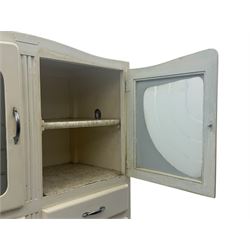 Mid-20th century painted kitchen cabinet, moulded top above a pair of glazed cupboard doors with stylised arrow motif panels, over two drawers and a fall-front cupboard, the lower section with twin cupboard doors
