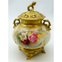  Royal Worcester two handled pot pourri vase and cover, the pierced quatrefoil shaped cover having rosebud finial, the bulbous body painted with roses and lilies amongst foliage by Reginald Austin, on four naturalistic gilded feet, c1913, H21cm   