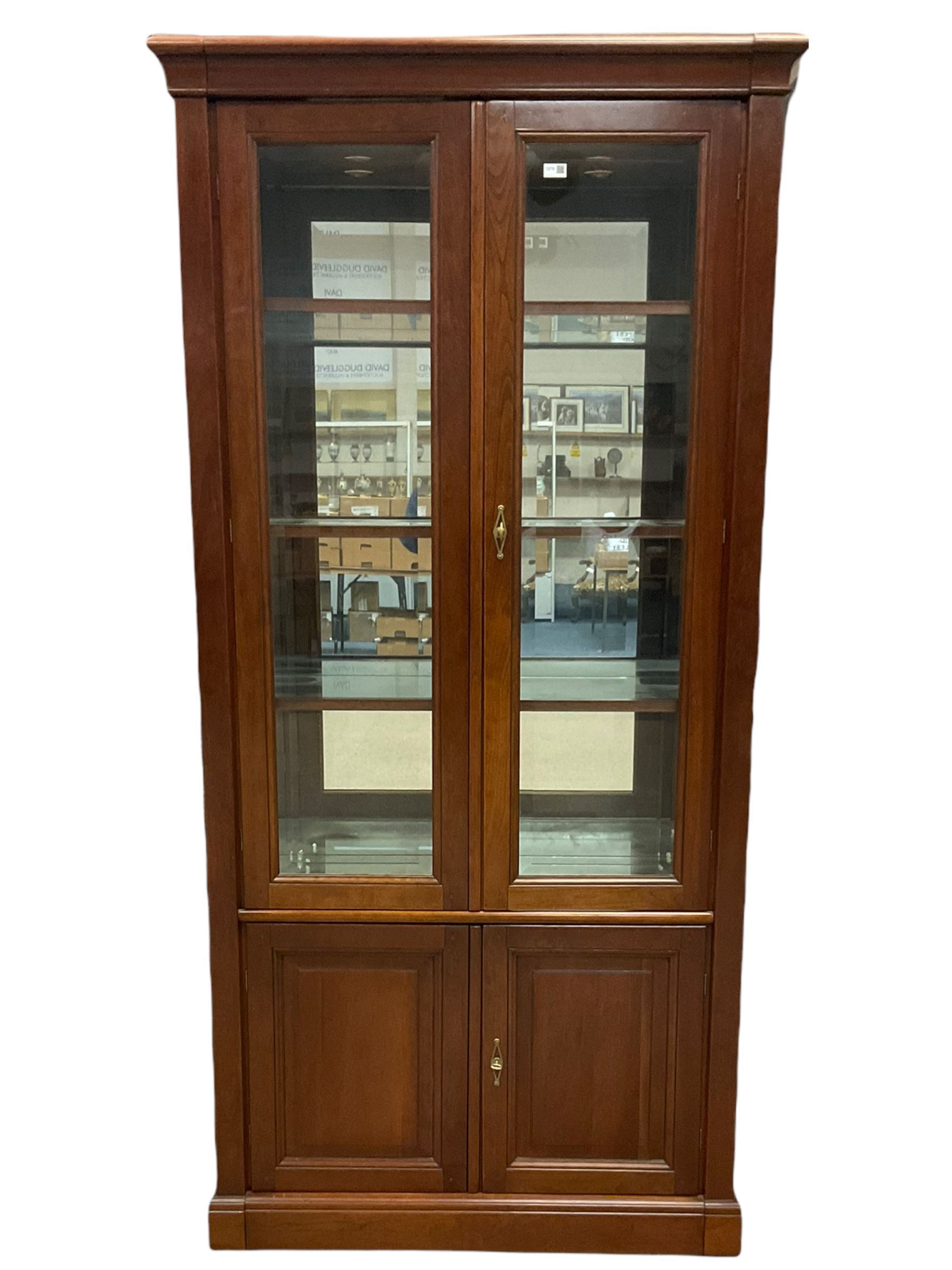 Grange Furniture - cherry wood finish display cabinet, two bevel glazed doors enclosing mirrored interior with glass shelves, double panelled cupboard below, on plinth base