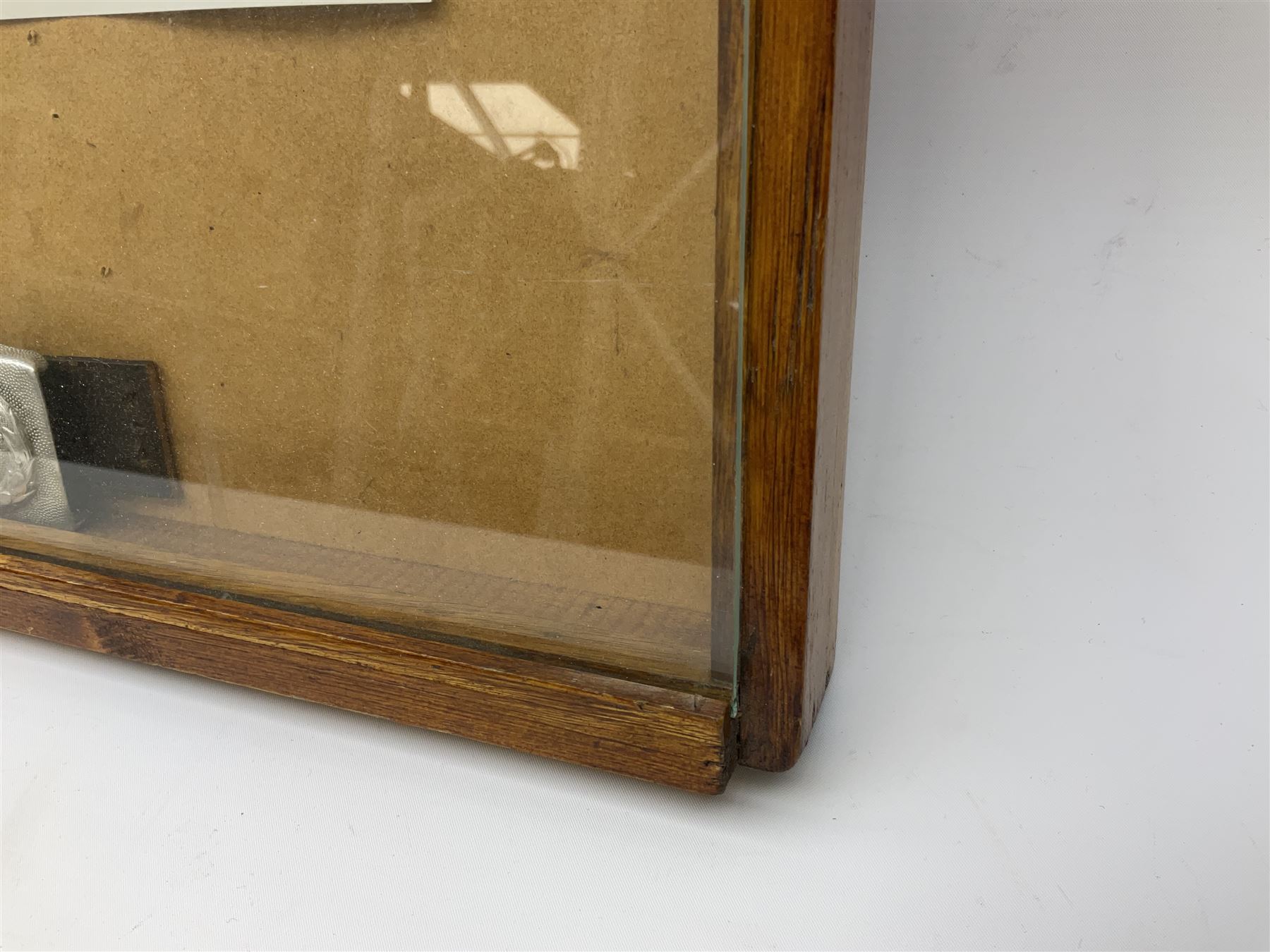 Display of eleven German belt buckles including 'SS', Party Buckle, two Army, Fire Service, two Luftwaffe, NSKK, Hitler Youth and WW1 Army; framed with three cloth badges and an armband