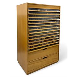 Large beech haberdashery thread storage cabinet, rectangular form with fourteen glass-fronted sloping drawers housing an extensive array of thread spools in assorted colours, over two larger drawers, raised on plinth base