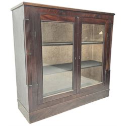 Edwardian mahogany enclosed bookcase, fitted with two glazed doors enclosing two shelves, flanked by reeded uprights, on skirted base