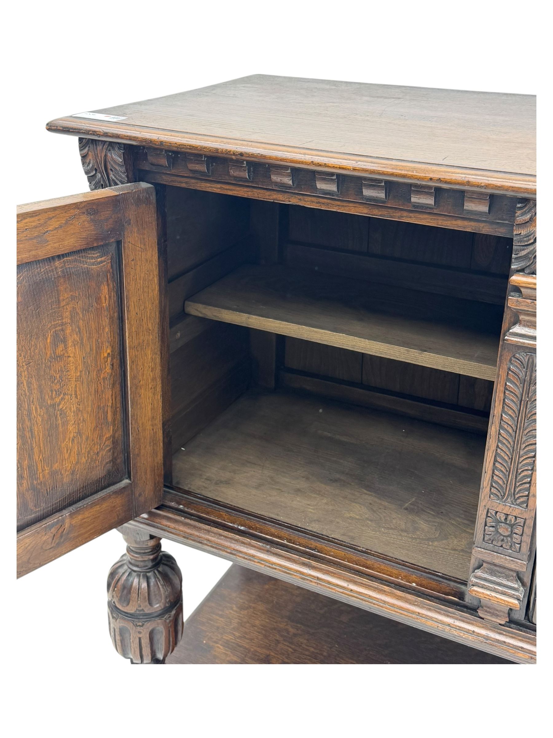Jacobean design carved oak two door cupboard, the frieze and twin cupboard doors carved with arcaded panels and stylised foliage, raised on baluster supports united by an undertier
