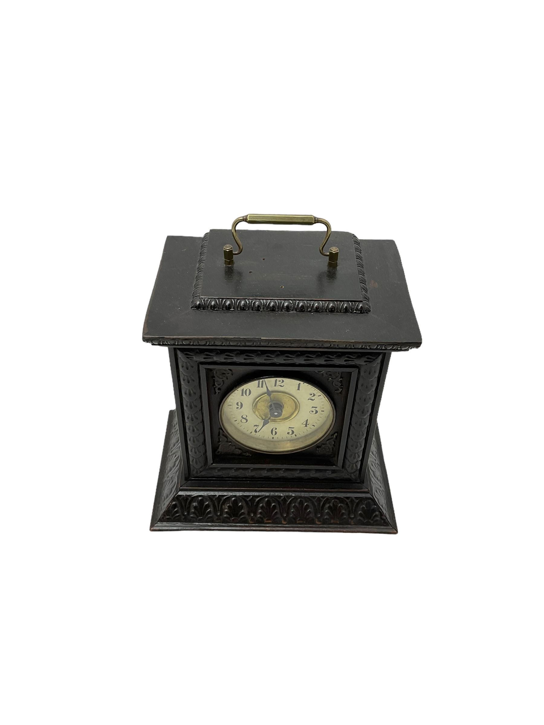 German - late 19th century  Black Forest Junghans alarm clock, profusely carved mouldings with glass side panels and carrying handle, two part dial with a gilt centre, Arabic numerals, minute track and steel spade hands, 30hr  balance wheel movement with alarm sounding on a bell, wound and set from the rear, with Key.