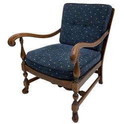 Early 20th century stained beech framed armchair, cane panel back over scrolled arm terminals, raised on turned supports united by turned H-stretcher, with patterned blue upholstered loose back and seat cushions