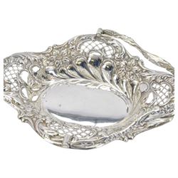 Edwardian silver swing handled basket, of oval form with shaped rim, embossed with floral decoration and with pierced latticework sides, upon four pad feet, hallmarked Chester 1905, maker's mark worn and indistinct
