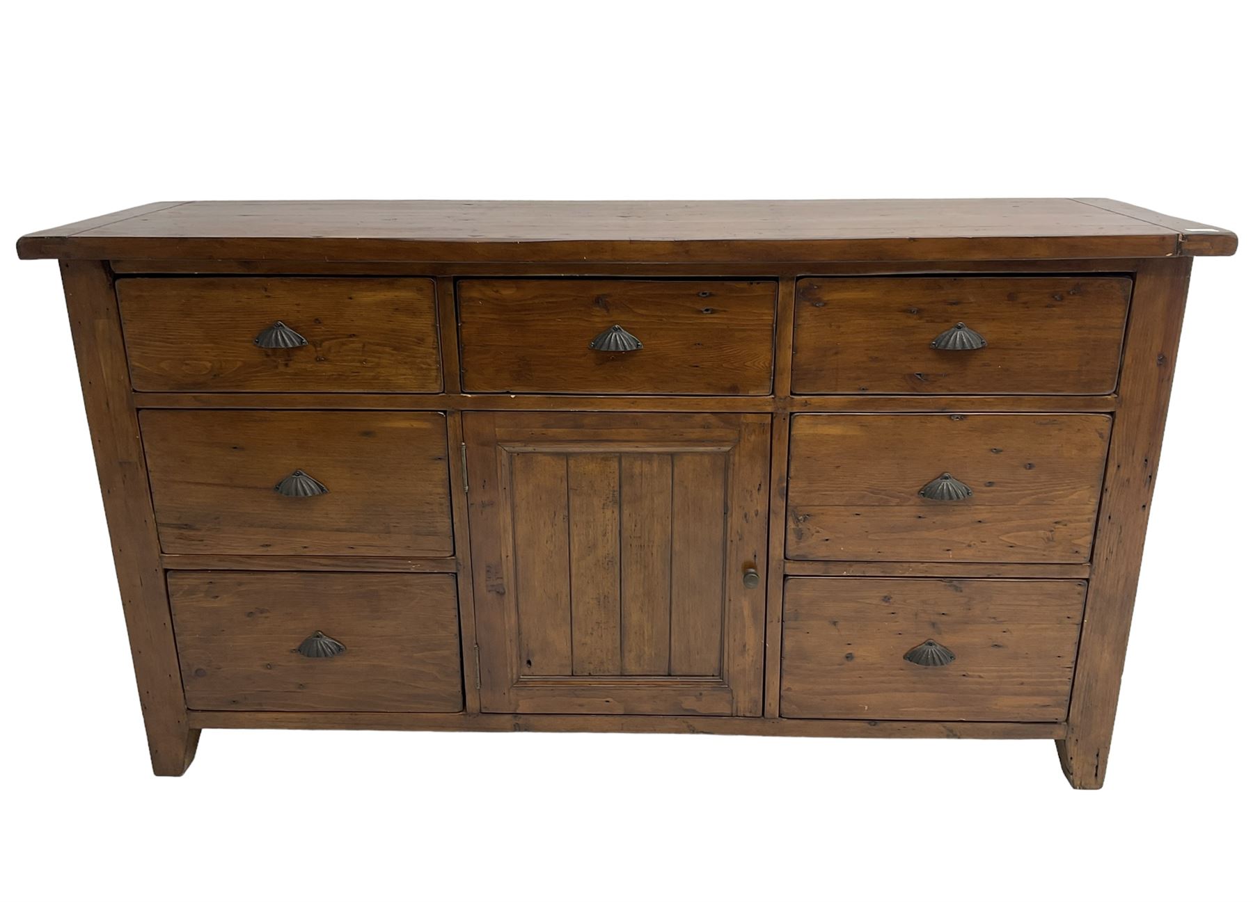 Stained pine rustic sideboard, rectangular top over seven drawers and single panelled cupboard, fitted with shell handles