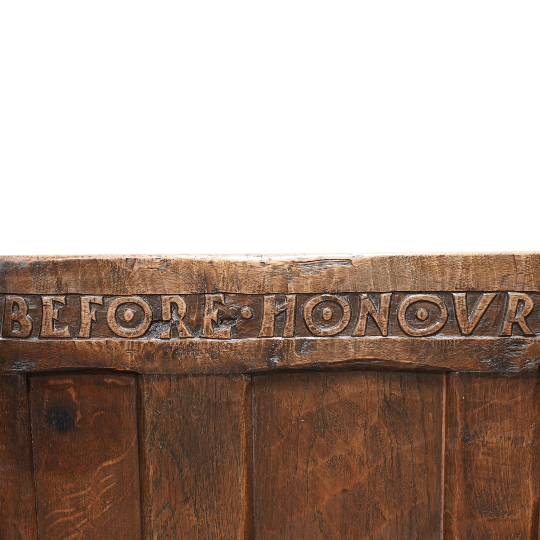 Mouseman - circa. 1920s adzed oak settle or bench, the cresting rail carved with inscription 'Before Honour is Humility', four panel back and plank seat on shaped end supports carved with grotesque masks terminals, carved with mouse signature, by Robert Thompson of Kilburn 
