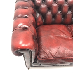  Three seat Chesterfield settee, upholstered in deep buttoned oxblood leather, turned supports on castors, W180cm  