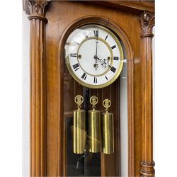 German- Late 19th century 8-day walnut cased Vienna regulator wall clock c1870,  with a broad arched pediment and heavily carved grotesque to the centre, carved frieze beneath with reeded columns to the front of the fully glazed door, carved ogee plinth and pendants to the base, two part enamel dial with Roman numerals and pierced steel hands, ebonised pendulum rod with a brass faced bob and beat plate, three matching brass cased weights and pulleys, grand sonnerie three train striking movement with a deadbeat escapement striking the quarters and hours on two coiled gongs. 
With repeat work.