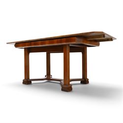 Art Deco walnut extending dining table, book-matched veneered shaped top, raised on cluster-column supports, united by stretchers, additional leaf extends to 185cm  