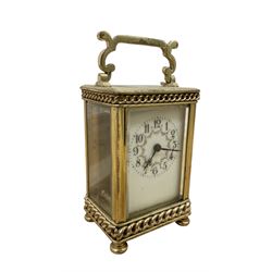 French- Edwardian 8-day carriage clock c1910, with recessed chain decoration and a serpentine handle, four recessed glass panels raised on bun feet, decorative enamel dial with floral swags, Arabic numerals and matching steel hands, single train movement with a cylinder platform escapement. With key.