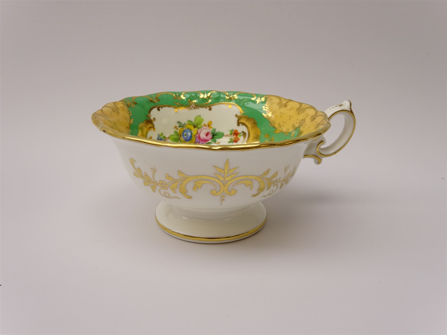 19th century Minton tea set, comprising twelve teacups, eleven saucers, fifteen side plates, cream jug, slop bowl, and two cake plates, decorated with panels of floral sprays, upon a green ground, heightened with gilt throughout, with printed puce mark beneath, and pattern number 5329

