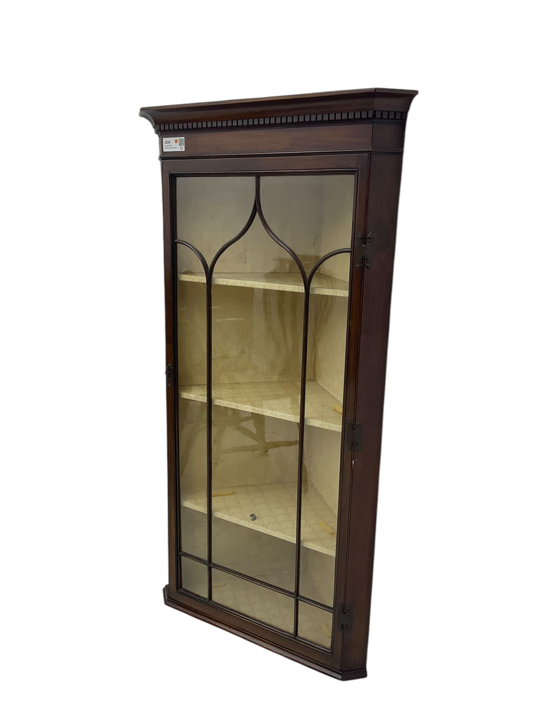 Early 20th century Georgian design mahogany wall-mounted corner display cabinet, projecting cornice with dentil frieze over astragal glazed door enclosing three fabric-lined shelves