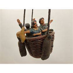 Painted wooden hanging model of a hot air balloon group, the balloon above a wicker basket complete with sandbags and figures, together with a similar example with a clown figure below, H68cm